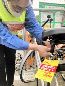 未施錠の自転車のカギ部分にメッセージタグを取り付ける市職員＝尼崎市内