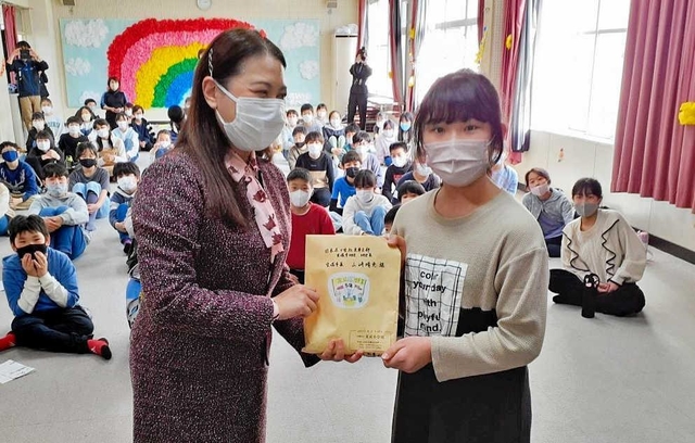 山崎晴恵市長（左）に売上金を手渡す児童＝末成小学校