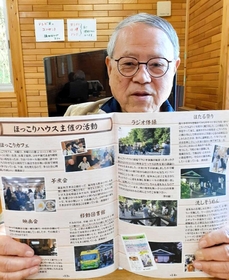 オープン１０年を祝う記念誌を手にする前館長の大浜憲司さん＝宝塚市中山台１