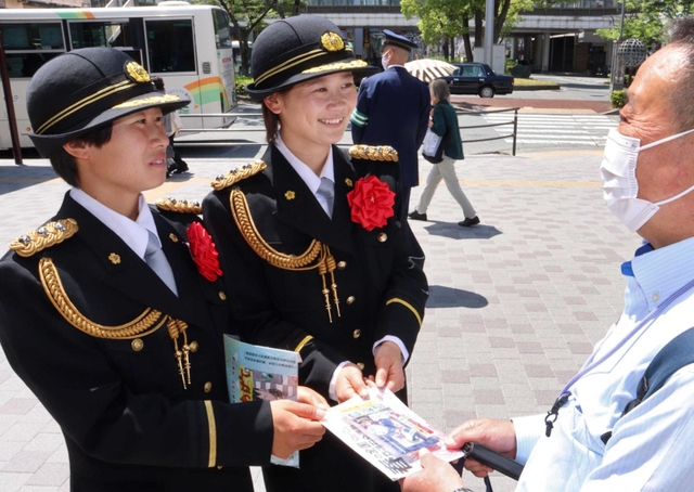 交通安全を呼びかけてチラシを手渡す園田学園女子大学ソフトボール部の（左から）保谷蓮さん、中川唯さん＝尼崎市南塚口町２