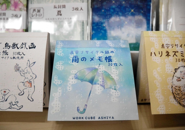 リサイクルされた点字紙の小さな突起をデザインに取り込んだメモ帳＝芦屋市公光町