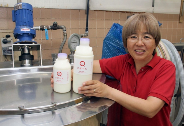 たからづか牛乳の本社工場で製造した牛乳を手にする社長の山本陽子さん＝宝塚市高司５