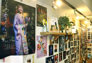 宝塚南口店の店内の壁は、宝塚歌劇のカレンダーやはがきで埋まっている。手前に大きく映るのは花組トップ娘役星風まどかさん＝宝塚市南口２