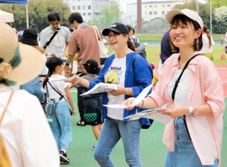 チラシを配る三宅奈緒子さん（右）ら「みんなのあま咲き放送局」のメンバー＝尼崎市西長洲町１