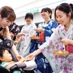 参拝客に笑顔でビワを配るびわ娘＝西宮市本町