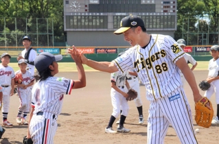 尼崎北ロータリークラブが主催した野球教室で子どもたちを褒める阪神タイガースの前監督、矢野燿大さん＝尼崎市西長洲町１、ベイコム野球場