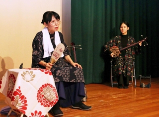 深優さんの三線に合わせ、母のカヅさんを演じる奥浜恵子さん（左）＝尼崎市塚口町３
