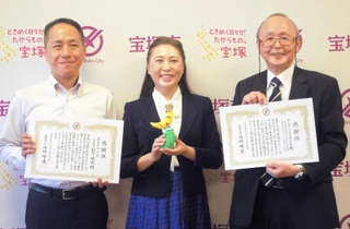 感謝状を受け取った「フクユ」の松下誠吾社長（左）と「ランランバスを守る会」の青木賢一会長（右）、山崎晴恵市長＝宝塚市役所