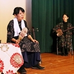 深優さんの三線に合わせ、母のカヅさんを演じる奥浜恵子さん（左）＝尼崎市塚口町３