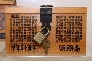 淡路島と記されているのに正面や側面は学年別漢字で埋め尽くされている木箱型の貯金箱＝尼崎市西本町北通３