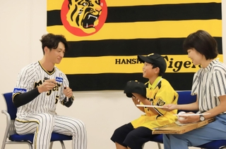 阪神タイガースの近本光司外野手（左）から色紙や帽子にサインをもらった板垣諒士郎君（中央）と母理絵子さん＝西宮市甲子園町（撮影・吉田敦史）