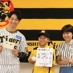 阪神タイガースの近本光司外野手（左）にインタビューし、色紙やボールにサインをもらった板垣諒士郎君（中央）と母理絵子さん＝西宮市甲子園町（撮影・吉田敦史）