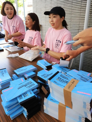 求められた商品券の冊数を手際よく渡す苦楽園ストアーズミーティングのスタッフたち＝西宮市南越木岩町