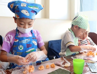 真剣な表情でデコ巻きずしを作る子どもたち＝伊丹市南野北５