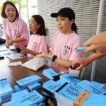 求められた商品券の冊数を手際よく渡す苦楽園ストアーズミーティングのスタッフたち＝西宮市南越木岩町