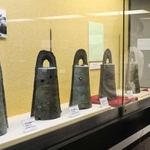 弥生時代に祭りで使われたとされる銅鐸が並ぶ会場＝辰馬考古資料館