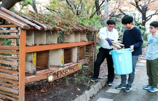 インセクトホテルの部屋から竹を取り出す森野光太郎さんと、科学研究部の生徒たち＝県立伊丹高校
