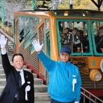 手を上げて電車の出発を合図する能勢電鉄の西中哲郎社長（左）ら＝川西市黒川
