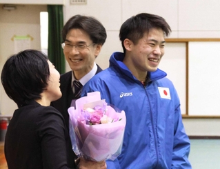 恩師の田中悠子さん（左）と大江誠さん（中央）に花束を渡してはにかむ岩渕緒久斗さん＝尼崎西高校