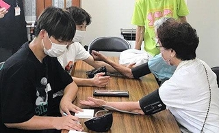 高齢者の見守り活動で健康チェックをする学生（関西国際大提供）