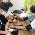 高齢者の見守り活動で健康チェックをする学生（関西国際大提供）