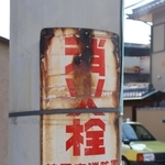 住宅街の電柱に付けられた消火栓の古びた看板。下には大手百貨店「三越」のマークと文字もある＝芦屋市大原町