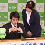 芦屋税務署の職員（右）の説明を受けながらスマートフォンで確定申告の模擬体験をする高島崚輔芦屋市長＝芦屋市役所