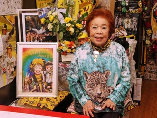 ２００３年の写真と並ぶ「トラのおばちゃん」こと引田孝子さん。自身の居酒屋には阪神グッズが並ぶ＝尼崎市西難波町６、尼のトラのおばちゃんの店