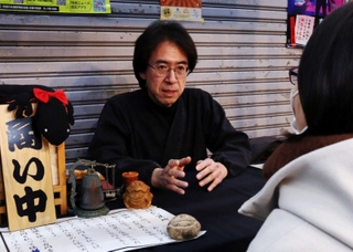 「怪談売買所」で客と話す怪談作家の宇津呂鹿太郎さん＝尼崎市杭瀬本町１、杭瀬中市場