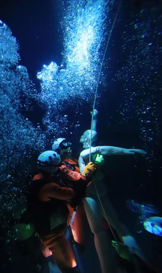 真っ暗な水中で訓練する救助隊員たち。海では濁りのため、ライトを使ってもほとんど見通せないという＝西宮市津門大塚町、西宮市消防署