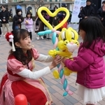 パフォーマーのあべよしえさん（左）からトラのバルーンアートを受け取る子ども＝西宮市甲子園町