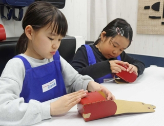 ミニランドセルを組み立てる子ども＝西宮市甲子園八番町、キッザニア甲子園