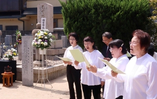義民碑前で「鳴尾義民頌歌」を披露する西宮さくらんぼ合唱団のメンバーら＝西宮市甲子園六番町、浄願寺