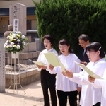 義民碑前で「鳴尾義民頌歌」を披露する西宮さくらんぼ合唱団のメンバーら＝西宮市甲子園六番町、浄願寺