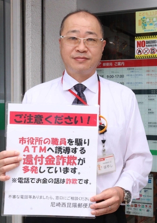 自作の注意喚起カードを提示しながら詐欺の可能性を説明した尼崎西昆陽郵便局の林康弘局長＝尼崎市西昆陽３