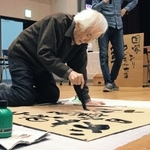 「ナクバ川柳」の墨書パフォーマンスをする木割大雄さん＝尼崎市長洲中通１、尼崎市立小田南生涯学習プラザ