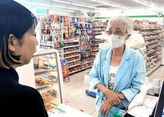 客になりきって電子マネーを買おうとする望月勝美さん（右）と応対した店長の立津千晴さん。訓練後に再現してもらった＝伊丹市堀池３