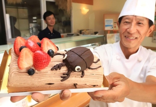 「ケーキ工房菓楽」の藤井隆志シェフ（右）が作る「里山オオクワガタロールケーキ」＝川西市東多田２