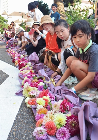 １列に花束を並べる参加者たち＝宝塚市栄町１、花のみち