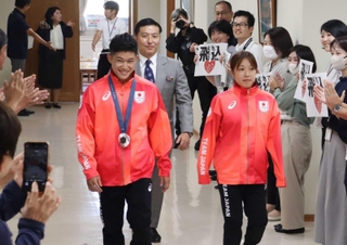 多くの市職員に拍手で迎えられた玉井陸斗さん（中央左）と荒井祭里さん（同右）。寺内健さん（中央）も出席した＝宝塚市役所
