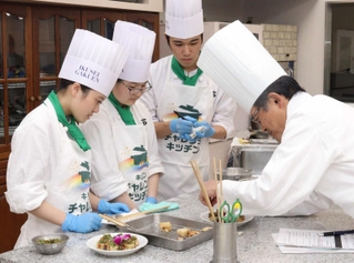 ホテル日航プリンセス京都の中埜智史総料理長（右）から指導を受ける生徒ら＝尼崎市開明町２