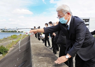 室戸台風で犠牲になった外島保養院の入所者らに向け、堤防沿いに水を手向ける参列者＝大阪市西淀川区中島２