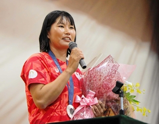 生徒から贈られた花束を手に話す吉岡美帆選手＝県立芦屋高校