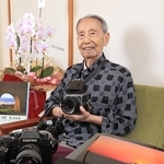 ハッセルブラッドなどの愛機を手に風景写真への思いを語る伊賀規さん。手前の作品はシベリア上空の機内から撮影した「オーロラ」＝西宮市郷免町