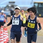 男子・尼崎市の１区山下慶馬選手（左）からたすきを受ける２区平野圭人選手＝加古川市の加古川河川敷マラソンコース（撮影・大田将之）