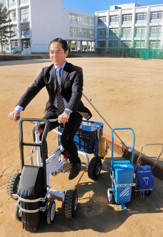 自身が発明したグラウンドチーターに乗る芦屋国際中等教育学校の川崎芳徳校長＝芦屋市新浜町