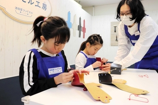 一針一針丁寧にひもを通す子どもたち＝西宮市甲子園八番町