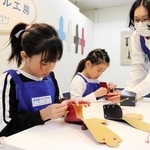 一針一針丁寧にひもを通す子どもたち＝西宮市甲子園八番町