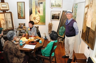 館内にはユタカ順子さんが描いた油絵の作品が並ぶ。右端が記念館を開いた阿部泰士さん＝西宮市甲子園六番町