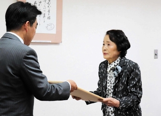 石井登志郎市長（左）から感謝状を受け取る女性＝西宮市役所